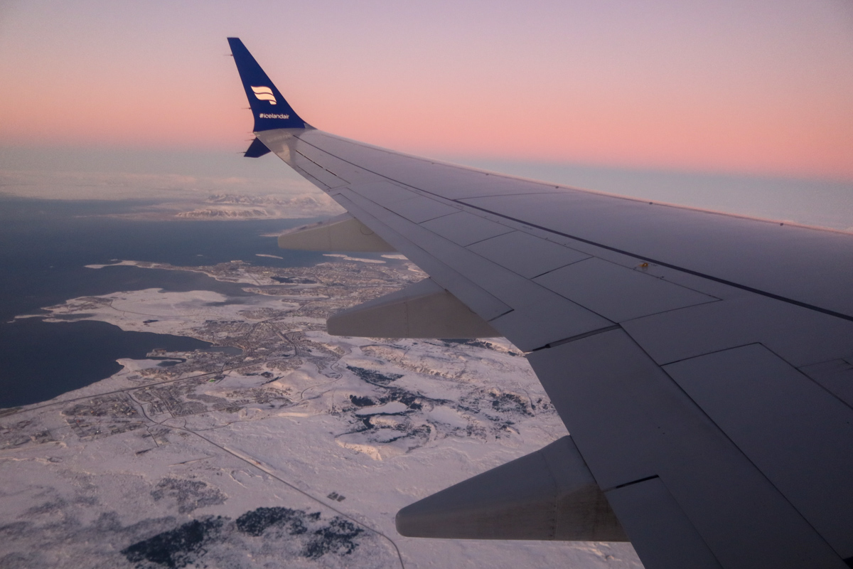 IcelandAir wing of a plane landing into the frozen country as the sun sets. 