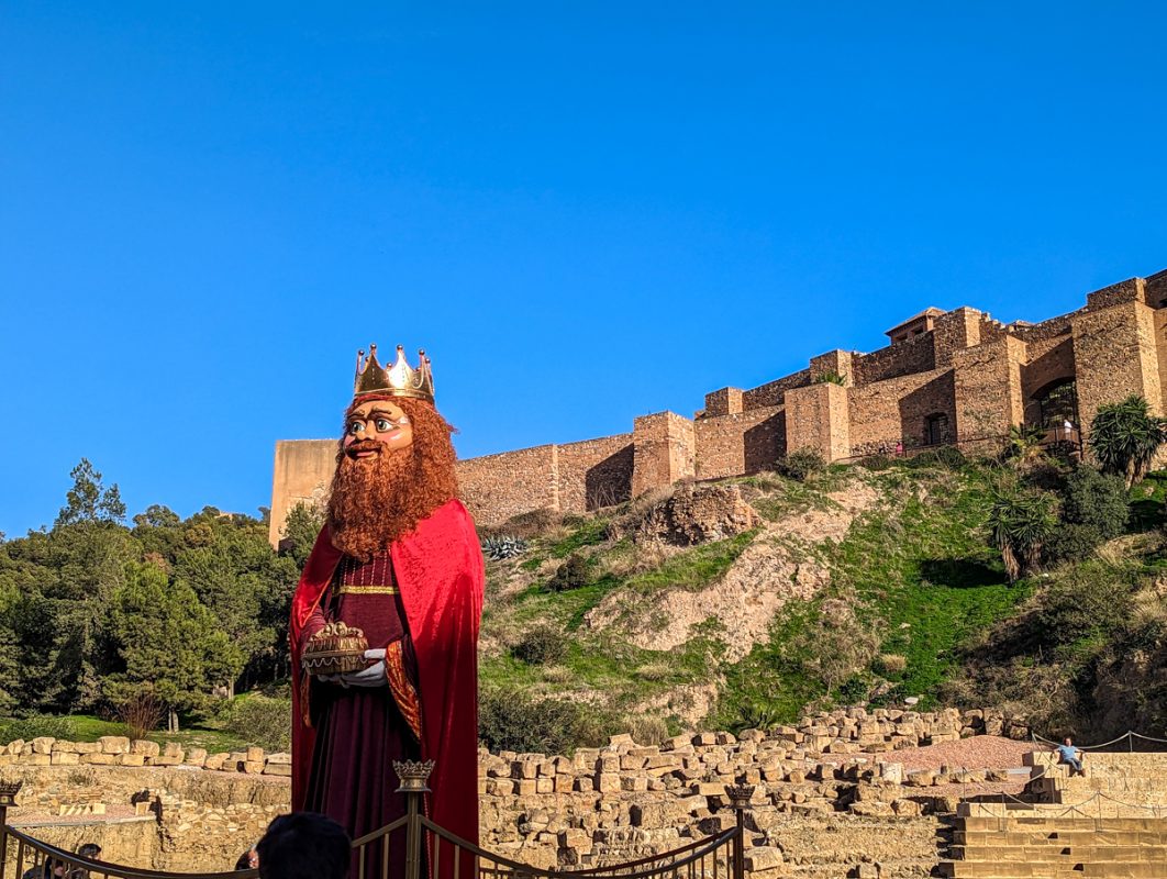 Bright blue skies in the background with the Alcazaba and the king in the foreground.