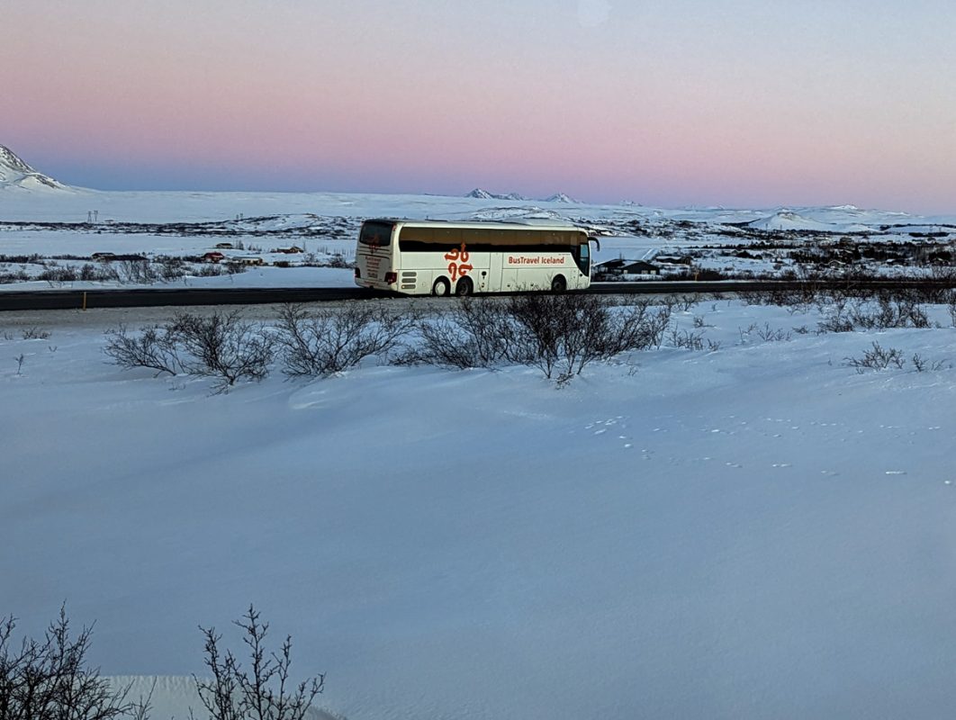 Tour bus in Iceland driving on one of the main roads, through a snowy landscape.