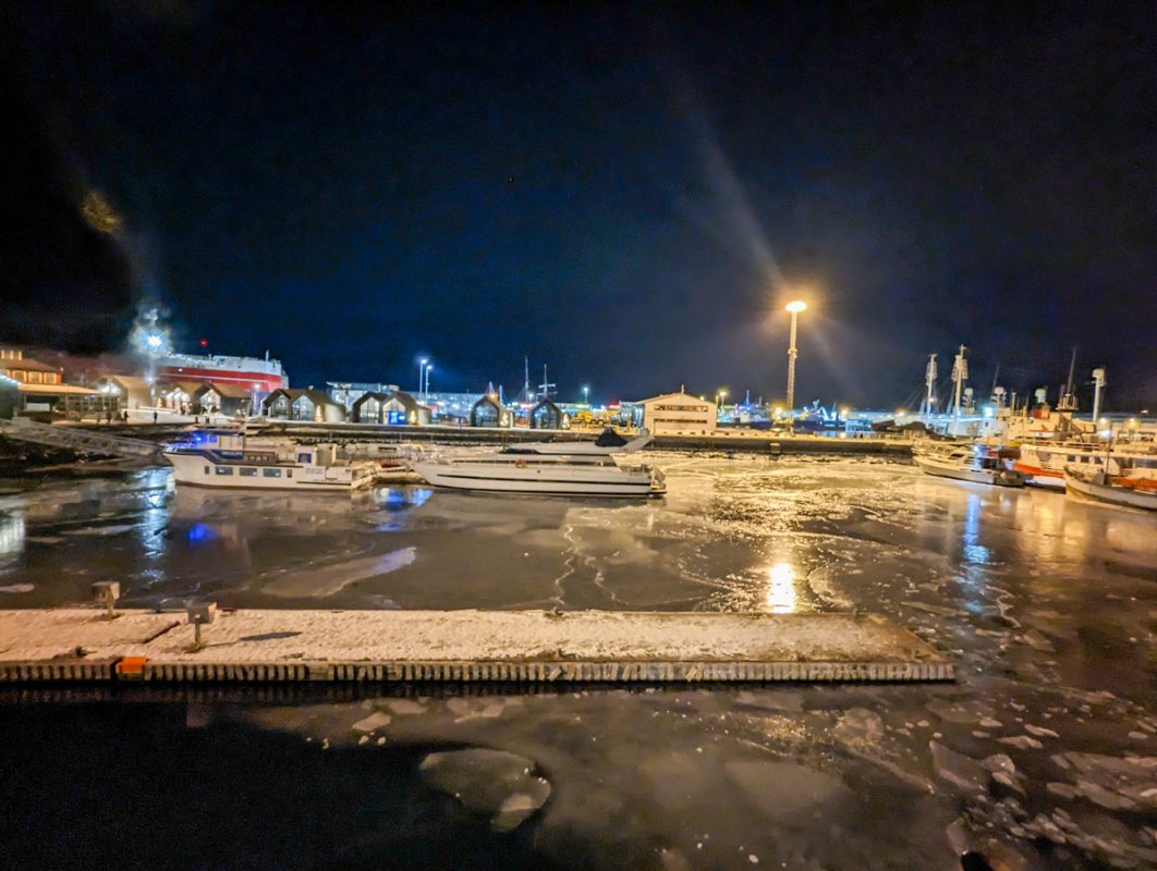 Night view of Reykjavik Harbour, with boats bobbing on the frozen water. 
