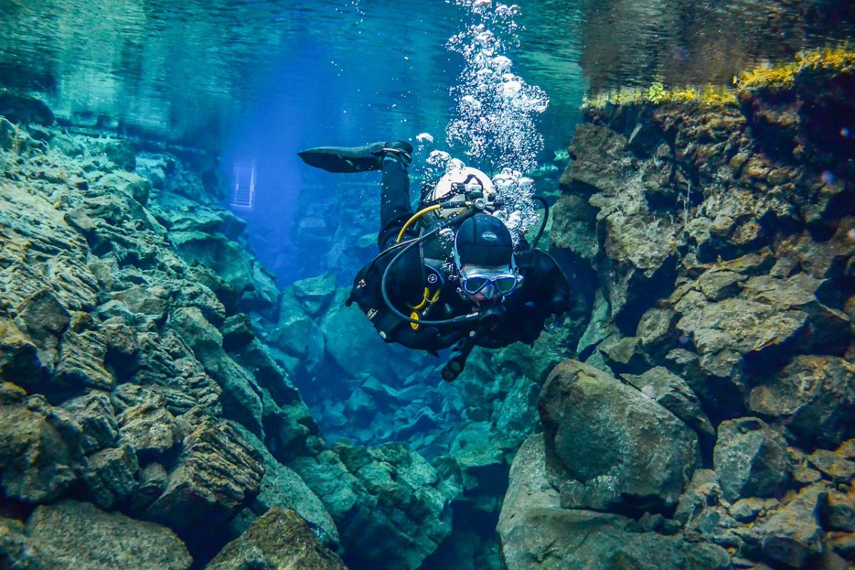 Person snorkelling through two tectonic plates in Iceland, whichi s one of the best diving destinations in the world.