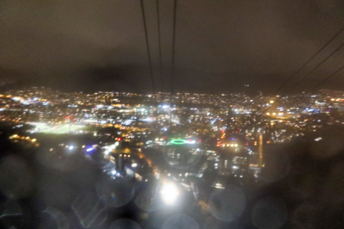 Cable car going up the mountain while the sky is dark and the city lights twinkle below