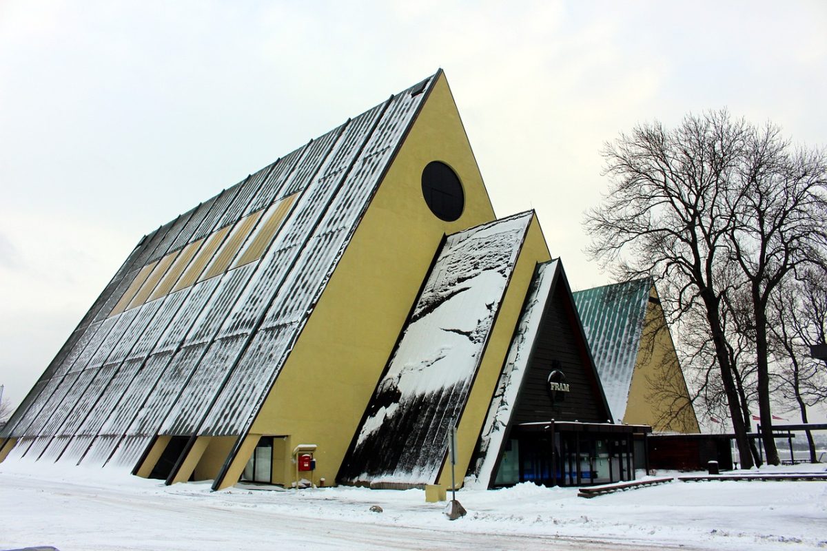 A triangular yellow building, covered in and surrounded by snow, in Oslo which is the capital city of Norway.