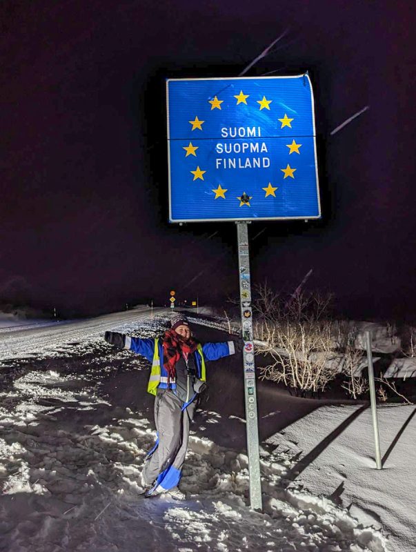 Claire standing next to the welcome to EU Finland sign in the snow