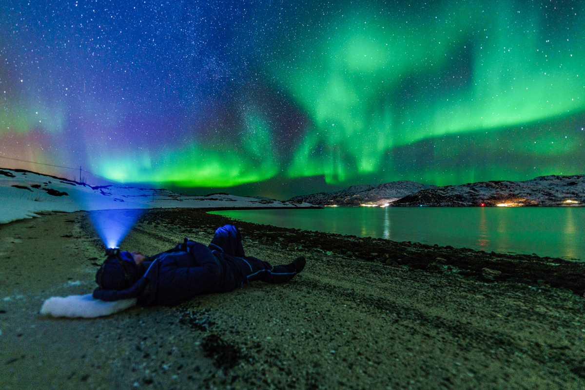 View of the green glowing northern lights on the horizon in Northern Norway