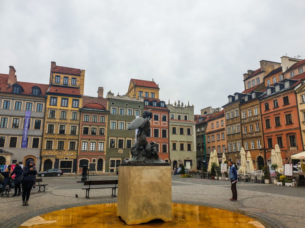 Old Town of Warsaw, with terraced coloured houses and a statue in the centre, in November. 