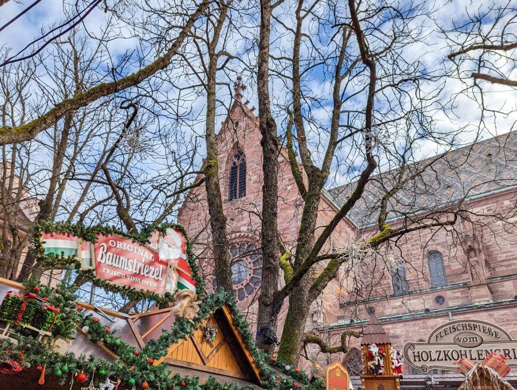 Christmas signs above huts in Basel in December, with a church in the background.
