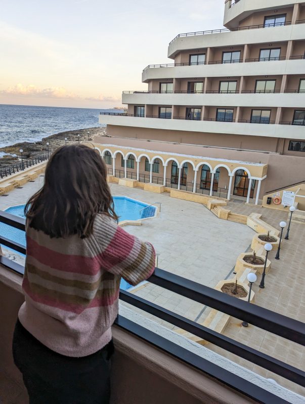 Girl standing on a balcony overlooking a pool and the beach at the Radisson Blu.
