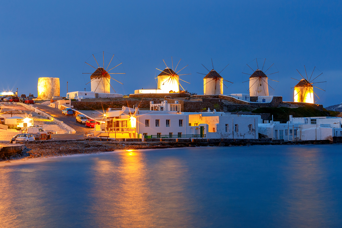 Traditional windmills on the beach in night illumination. Greece. Mykonos. Chora.